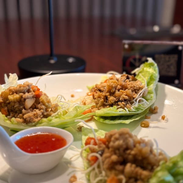 Thai lettuce wraps with minced chicken, vegetables, and a side of sweet chili sauce.