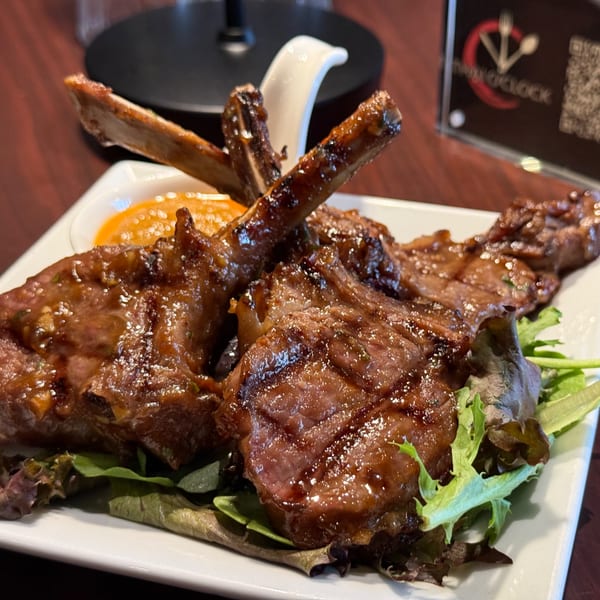 Grilled lamb chops with a sweet glaze, served on a bed of mixed greens with dipping sauce.