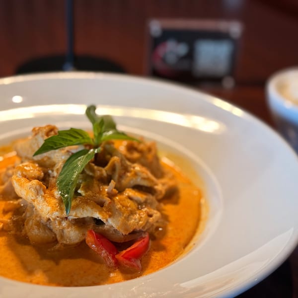Thai red curry with chicken, basil, and red peppers in a white bowl at Thai O'Clock.