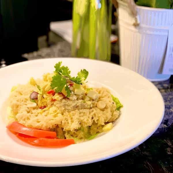 Crispy Thai salad with red bell pepper, cilantro, and chopped nuts on a white plate.